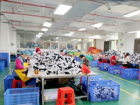 Quality control workshop where finished toys are sorted and inspected on long tables