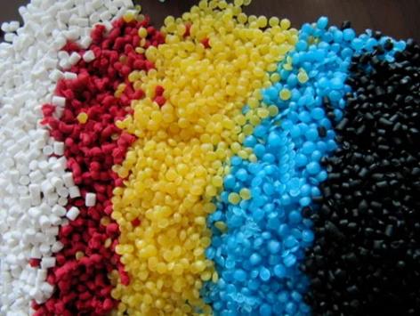 Coloured thermoplastic pellets in white, red, yellow, blue and black, the raw stock for moulded toy bodies